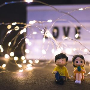 pexels-photo-9174647-9174647 Adorable couple figurines surrounded by warm glowing fairy lights with a 'LOVE' sign.